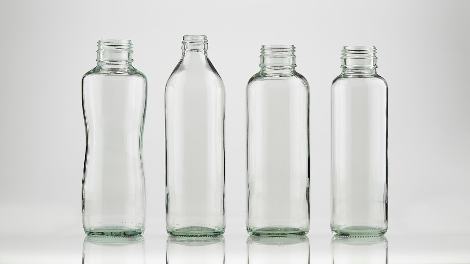 Clear beverage bottles with custom molds and screw-on caps.