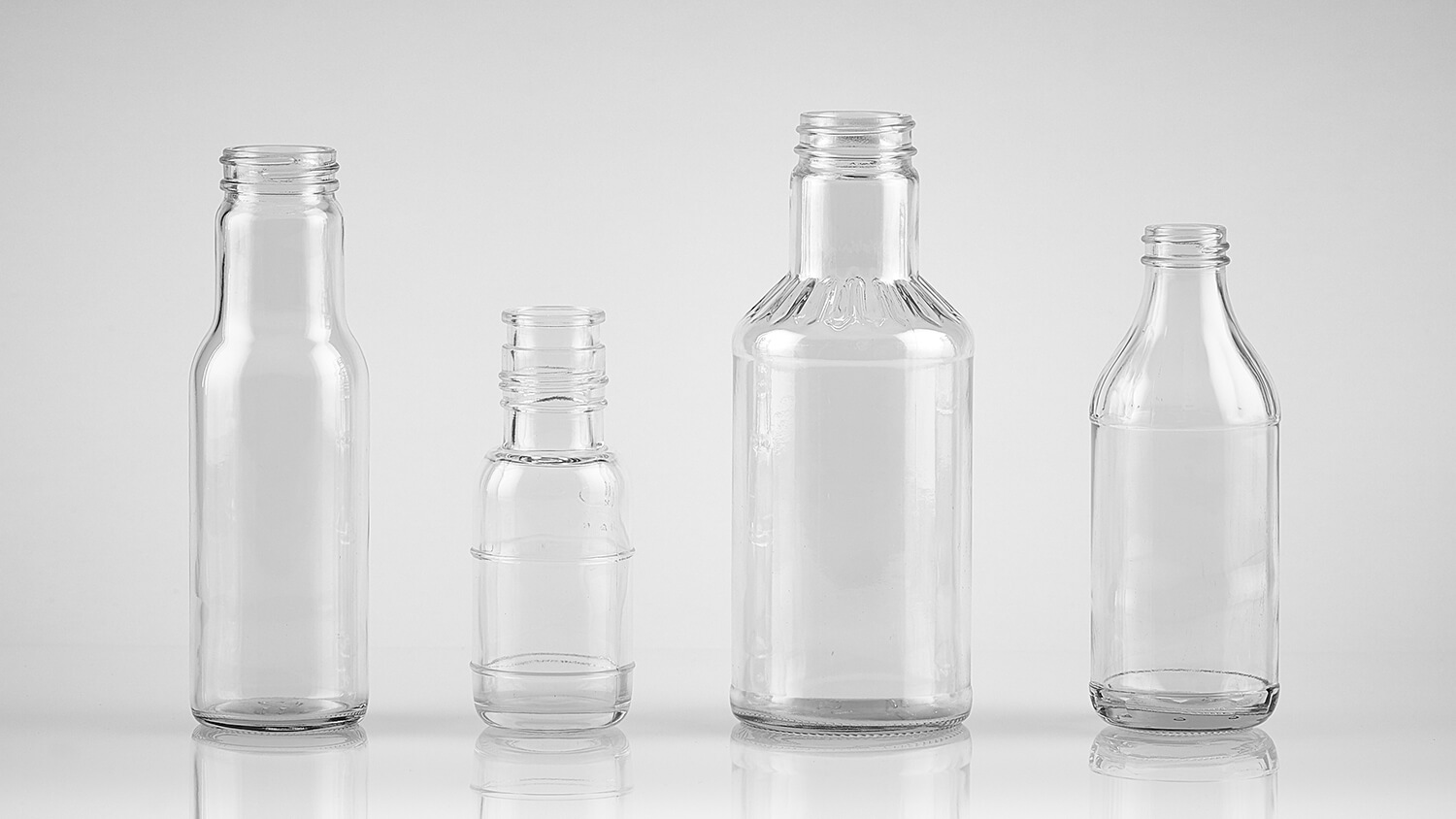 Custom glass bottle embossing with logos and unique shapes for food packaging.