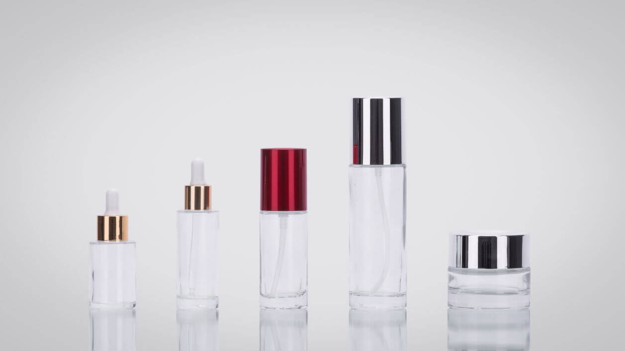 Clear cosmetic bottles in different shapes with colored caps.