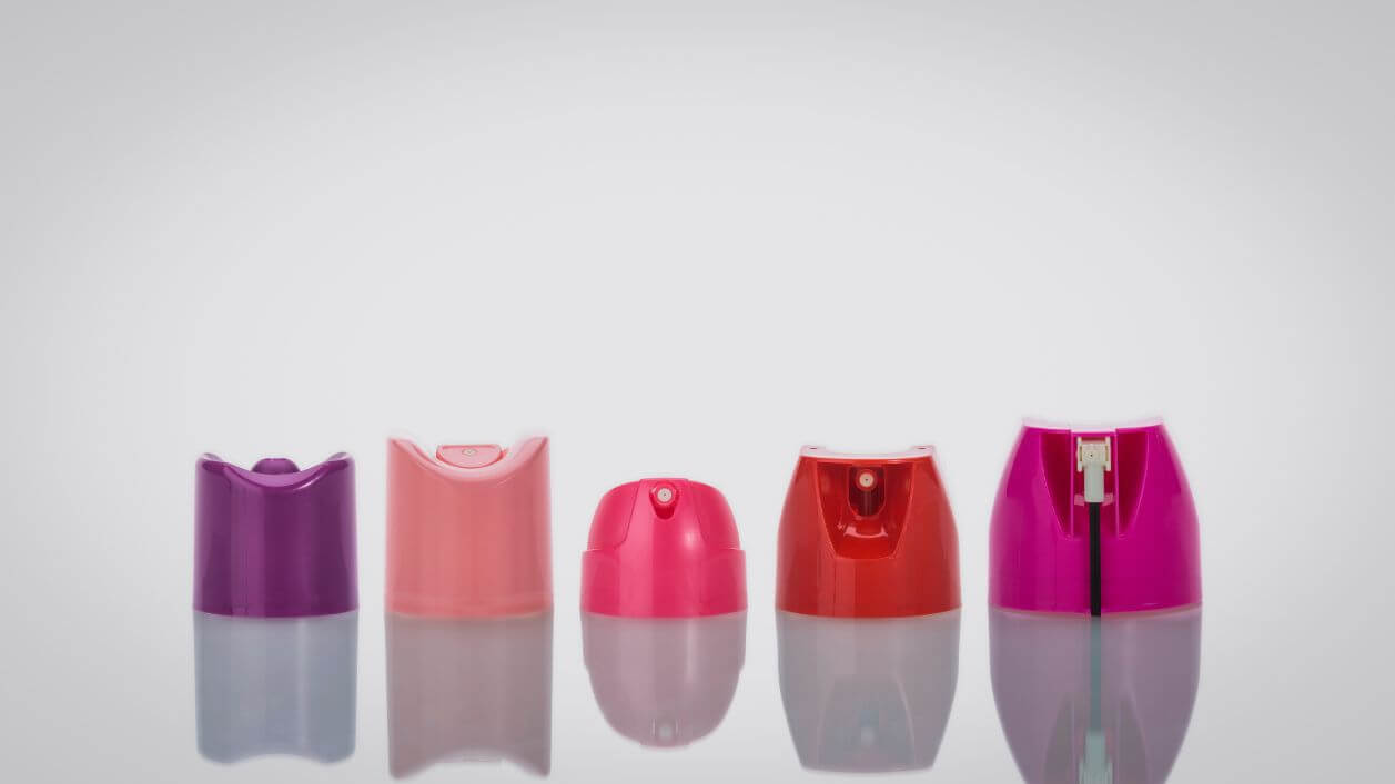 Pink and purple aerosol spray caps with decorative finishes for brand differentiation.
