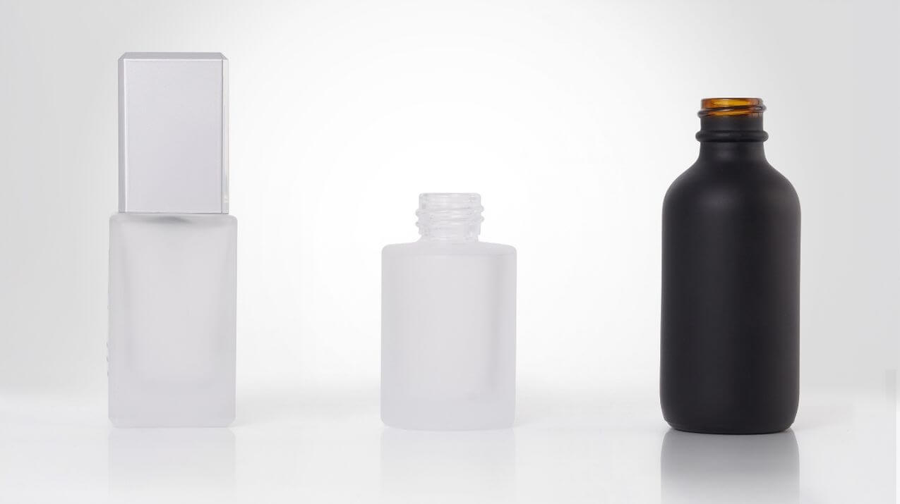 Frosted cosmetic glass bottles in different shapes and sizes.