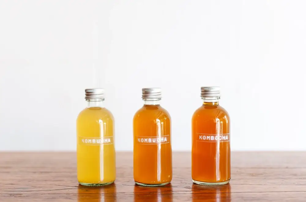Boston Round glass bottles, on a table, all filled with different-colored juices.