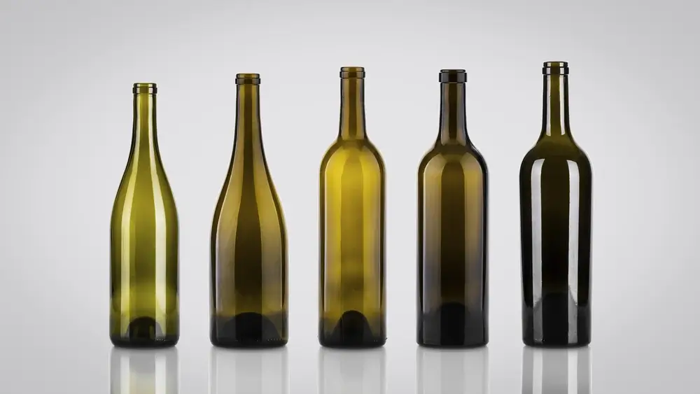 Different shaped and colored wine bottles, with five bottles in a row.