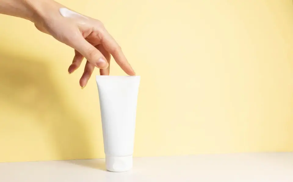 Plastic tubes on orange background with a hand touching the tube.