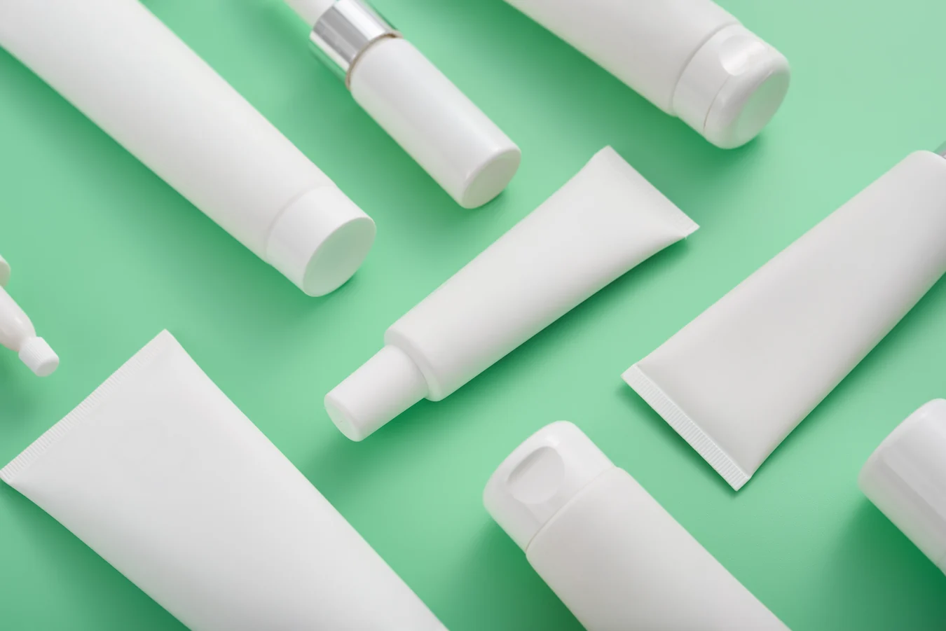 Personal care tubes and applicators with green background.
