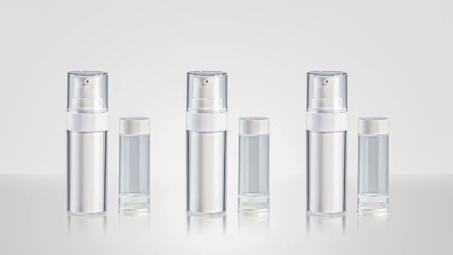 Refillable airless pump bottles with clear cylindrical outer shells, white inner cartridges, white pump dispensers, transparent overcaps, and removable refill containers shown beside each bottle.