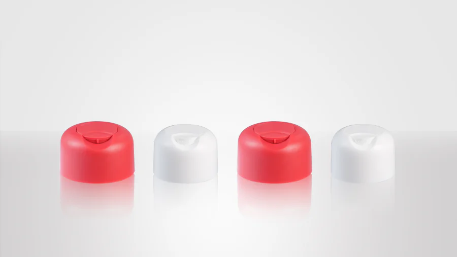 Red and white tamper-evident disc top caps with rounded housings and recessed press-to-open dispensing discs shown as standalone bottle closures.