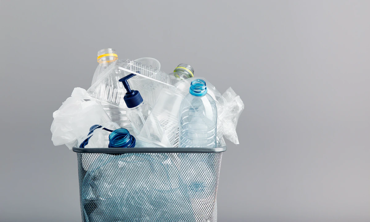 Empty plastic bottles, a pump bottle, and plastic film piled in a wire mesh waste bin